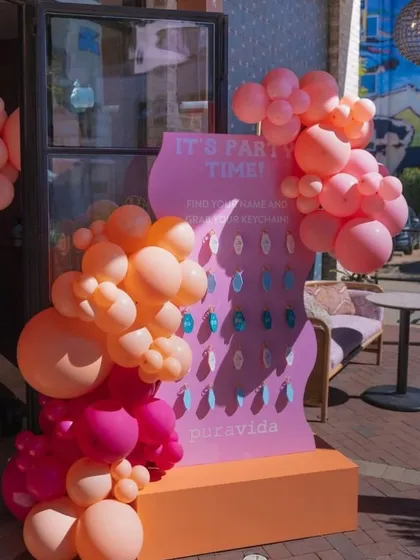 This 'It's Party Time' board for a brand pop-up allows guests to find their name and grab a personalized keychain, making them feel special and connected to the brand.