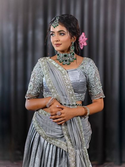 An elegant reception look featuring a silver-grey lehenga with emerald green jewelry. I teach my students how to create harmonious looks by balancing outfit, jewelry, and makeup.