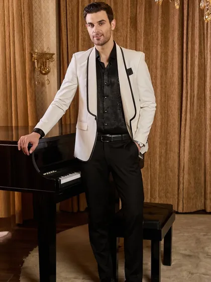 A timeless white tuxedo jacket with contrasting black shawl lapels, offering a sharp and sophisticated look for any cocktail party or reception. This bespoke piece is tailored for a clean silhouette that commands attention with quiet confidence.
