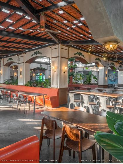 A wide view of the semi-open dining area at Adda 1522. The space is designed to feel like a time capsule of old Bangalore, with traditional Mangalore tiles, colonial-style arches, and lush plants.