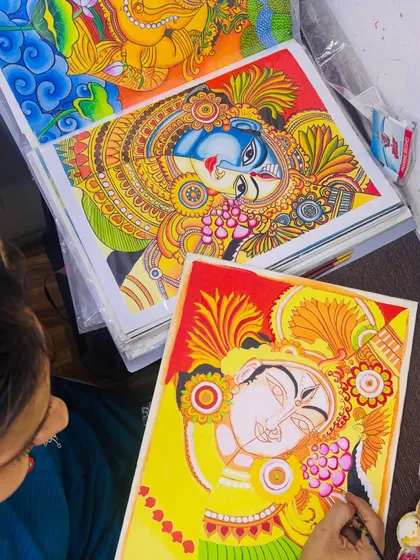 The beauty of Kerala mural painting is in the details. Here, a student carefully applies color, bringing a traditional deity to life, with a completed masterpiece inspiring her in the background.