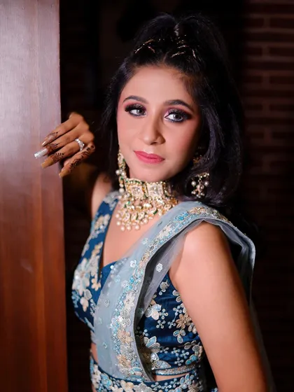 A posed shot showing the complete look: the blue floral lehenga, the statement jewellery, and the party-ready makeup.