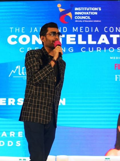 Standing and addressing the audience during the media conclave, ensuring the energy remains high throughout the event.