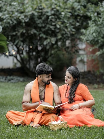 A candid interaction during the themed photoshoot, where the couple shares a book and a smile in a natural, grassy setting. This blends the epic theme with a simple, relatable moment.