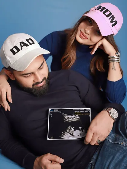 Let's have some fun with your announcement! Using props like these 'MOM' and 'DAD' hats along with your sonogram photo adds a playful and personal touch to your pregnancy photoshoot. It’s a cute way to share your joy with the world.