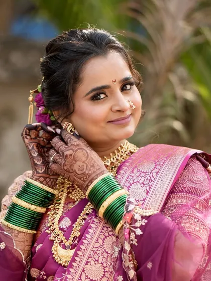 Meghana adjusting her earring, a classic bridal pose. Her monochromatic makeup and traditional jewelry are perfectly in sync.
