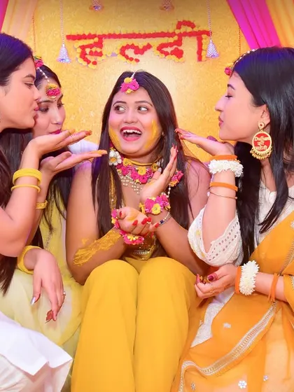 The Haldi ceremony is all about fun and family. We focus on capturing candid moments of joy, like this shot of the bride's friends playfully applying turmeric paste, a cherished memory from pre-wedding festivities.