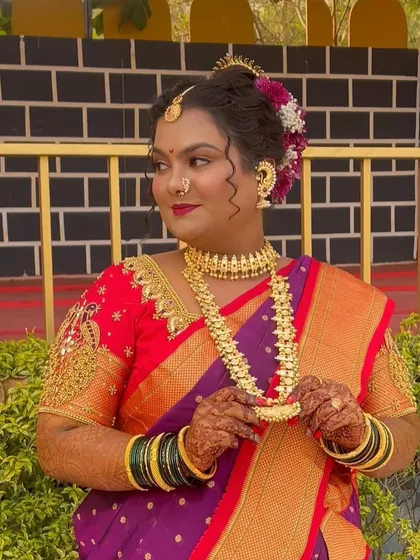 A beautiful portrait of the bride, showcasing her intricate gold jewelry and the flawless finish of her makeup. She looks every bit the royal Maharashtrian 'Navri'.