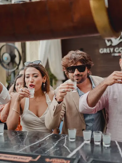The celebration begins. Friends and family take celebratory shots at the bar immediately following the successful surprise proposal, marking the beginning of a new chapter.
