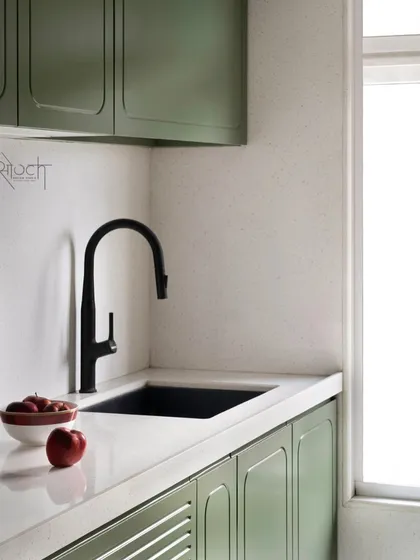 A minimalist shot of the olive green kitchen, focusing on the clean lines of the tap and sink.