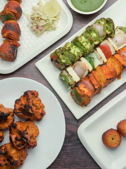 A look at some of our most requested North Indian appetizers. This platter features a variety of succulent tandoori items, including classic Paneer Tikka, creamy Malai Tikka, and flavorful Dahi Ke Kebab, all served with fresh green chutney.