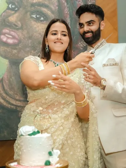 A joyous cake-cutting moment during an indoor engagement celebration in Pune. The couple's happiness is the focus, framed by modern decor and a beautiful piece of art, capturing the celebratory spirit of the occasion.