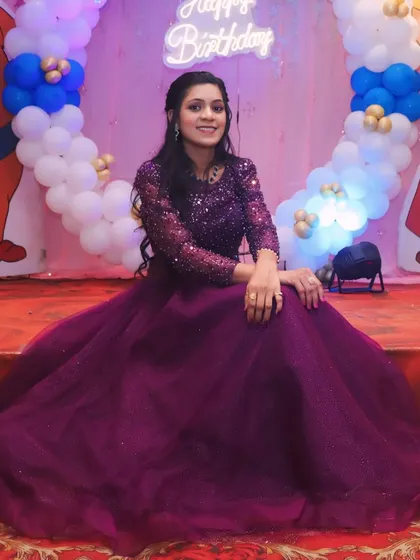 A seated portrait of the birthday girl in her gorgeous purple gown. The balloon backdrop adds to the festive and celebratory atmosphere.