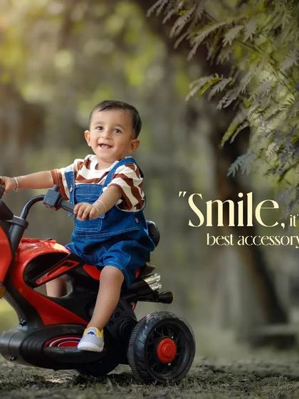 Smile, it's your best accessory. A happy boy on his red toy motorcycle, with his guitar resting against a nearby tree.