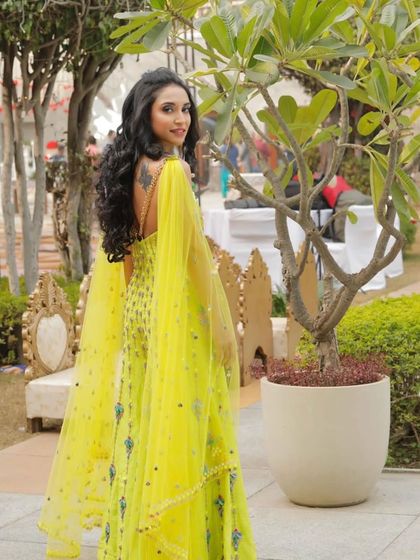 A full-length shot of the bride, showcasing her stunning yellow outfit and the joyful, glowing makeup look.