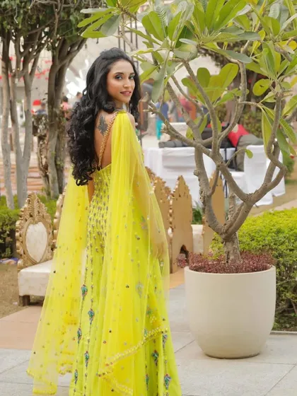 A full-length shot of the bride, showcasing her stunning yellow outfit and the joyful, glowing makeup look.