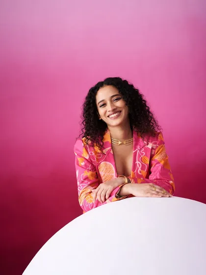 A bright and cheerful shot against a vibrant pink background. The makeup is fresh and subtle, with a focus on a genuine smile and glowing skin.