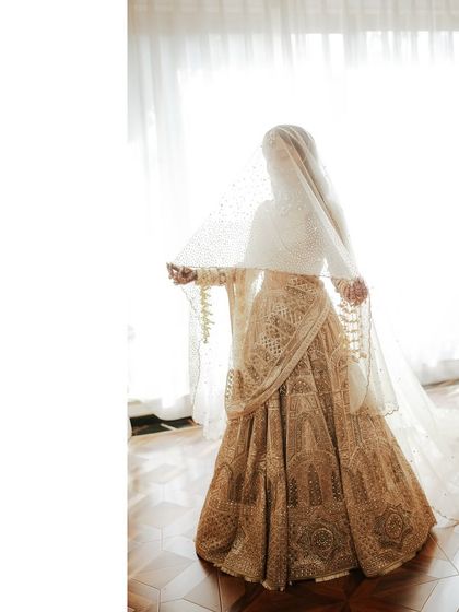 A full-length view of the bride's magnificent wedding lehenga. The long, flowing veil adds a touch of drama and grandeur, completing her stunning bridal look.