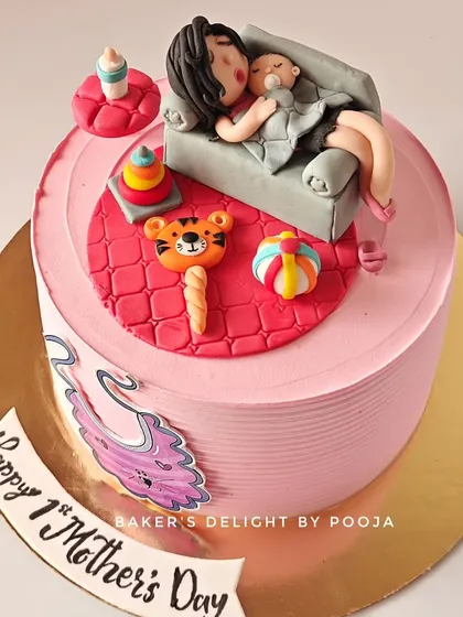 A cake that captures the beautiful chaos of new motherhood for a first Mother's Day. The topper shows a mom and baby cuddling on the couch, surrounded by tiny, edible toys like a tiger rattle and stacking rings.