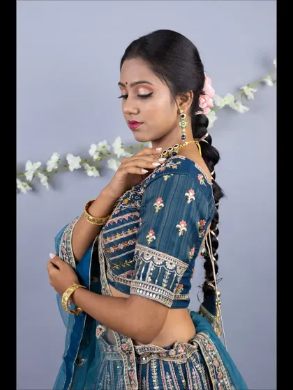 A close-up portrait showing the detailed embroidery on the blouse sleeve and the beautiful, long braided hairstyle.