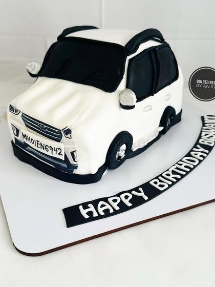 A fully sculpted cake in the shape of a white car, complete with a custom license plate.