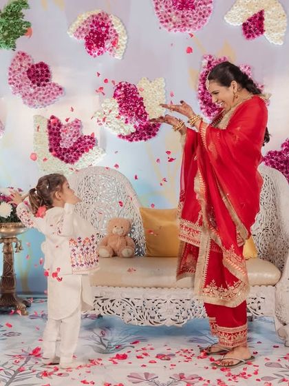 A playful and heartwarming moment between the mom-to-be and a little one, showering each other with flower petals in front of the beautiful floral backdrop.