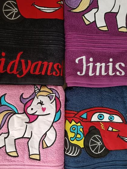 A set of four personalized kids' towels, showing the variety of designs and colors available.