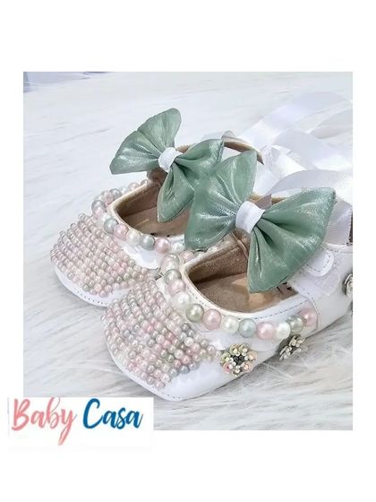 Step into comfort with our adorable, handcrafted baby shoes. These white bellies are embellished with pearls and a beautiful green bow.
