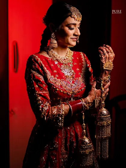 A portrait of the bride holding her kaleere. The dramatic red lighting adds a touch of glamour and highlights the emotion in her expression.