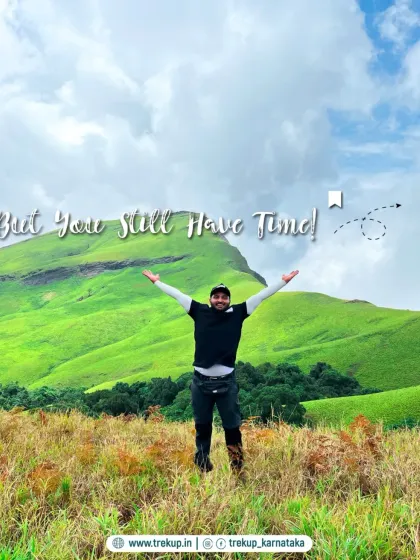 A trekker with arms wide open in a vast green field, representing the freedom and happiness you find on our trips.