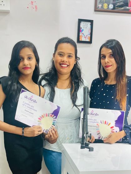Two graduates from my second batch, proudly holding their certificates and the nail art they created during the class.