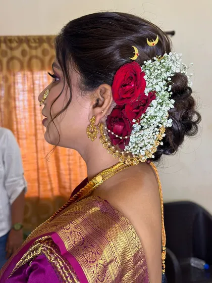 Another variation of the bridal bun, this time incorporating fresh red roses and crescent moon accessories for a divine look.