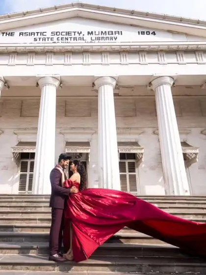 A timeless moment at Mumbai's iconic Asiatic Library. This deep maroon gown features a pleated yoke and a modern slit, offering a sophisticated and regal look for shoots in architectural settings.