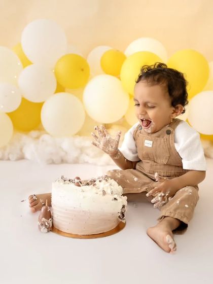 A moment of pure joy and laughter during the cake smash, capturing the fun and freedom of the experience.