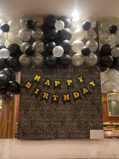 A dedicated photo backdrop for the restaurant party. I used a textured wallpaper as a base and added a 'Happy Birthday' banner with black and white balloon flowers.