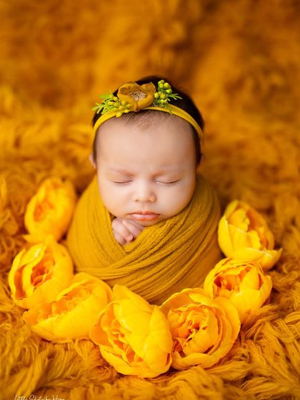 This baby is surrounded by a ring of beautiful yellow tulips, creating a stunning and artistic floral portrait.