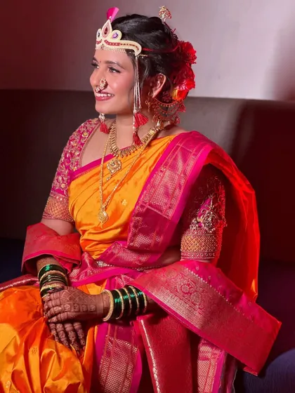 A seated portrait showing the full effect of the Nauvari saree and the complementary bridal makeup. The look is both traditional and comfortable.