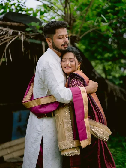 A comforting embrace between the bride and groom, both in traditional Maharashtrian wedding attire.