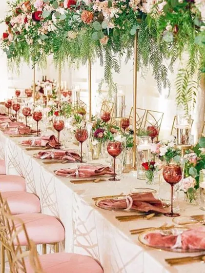 A long table setting defined by dusty rose chairs and dramatic, hanging floral arrangements. This setup showcases our ability to integrate decor and dining into a single, cohesive, and beautiful vision.