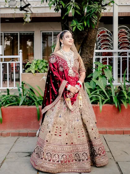 A full-length portrait of the bride looking regal in her heavily embroidered wedding lehenga.