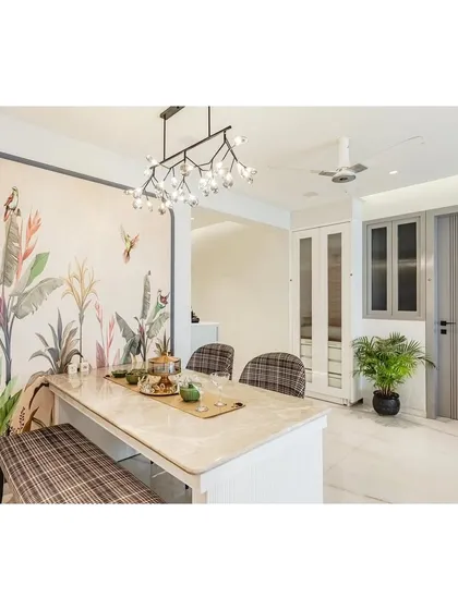 Dining spaces should feel special. For this project, I used a stunning tropical wallpaper to create a feature wall, framed to look like a piece of art. The Italian marble dining table, paired with plaid-upholstered chairs and a bench, adds a layer of timeless elegance, all under a modern branching chandelier.
