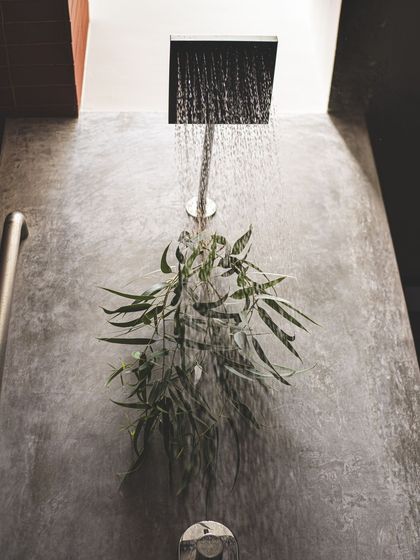 A detail of the rain shower, where a skylight above creates a unique bathing experience. The raw concrete wall and simple chrome fixture emphasize our commitment to a minimal and honest material palette.