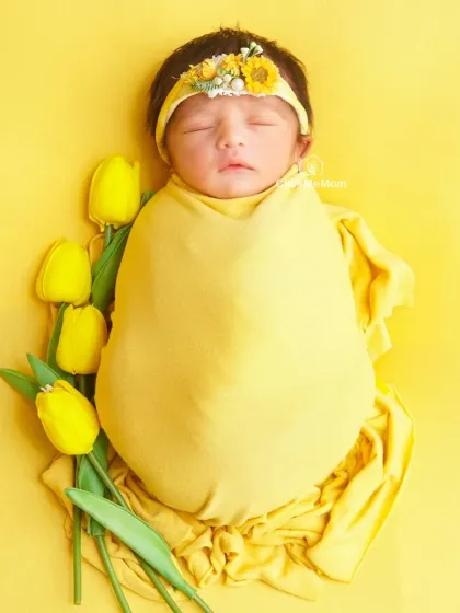 A full-body shot of the yellow tulip theme, showing the baby perfectly swaddled and looking like a little flower bud herself.