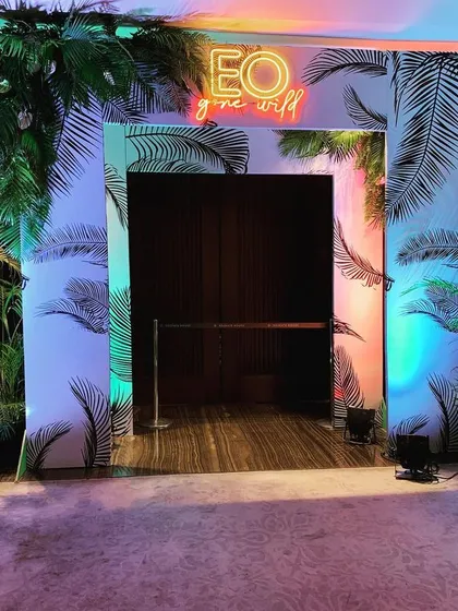 The entrance to the 'EO Gone Wild' gala, designed to immediately immerse guests in the theme with a custom-printed archway and colorful, dramatic lighting.
