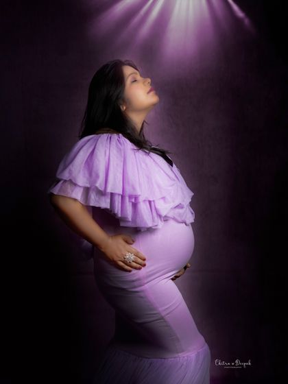 Bathed in a purple spotlight. This dramatic lighting creates a powerful and artistic portrait, highlighting the mom-to-be's profile and bump.