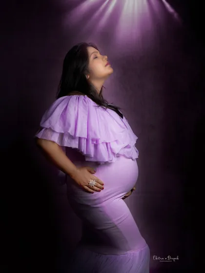 Bathed in a purple spotlight. This dramatic lighting creates a powerful and artistic portrait, highlighting the mom-to-be's profile and bump.