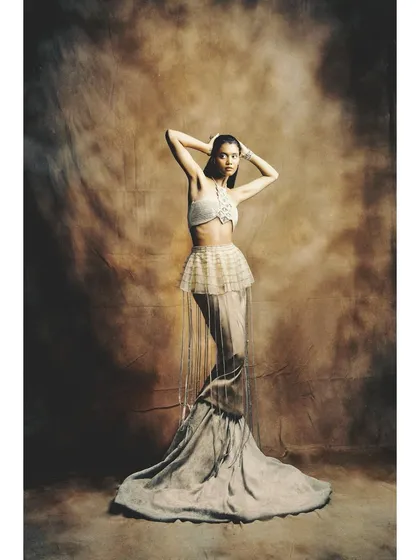 A powerful pose from the 'Sandcastles' editorial. The styling combines a macrame top with a layered, flowing skirt, creating a look that is both earthy and ethereal.