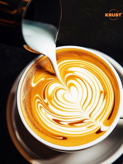 A stunning overhead shot of a barista pouring intricate latte art. This image perfectly captures the precision and beauty of the craft we teach.
