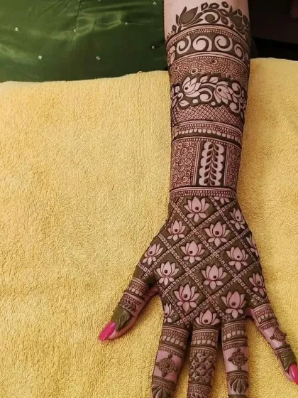 This full-arm bridal mehndi showcases our skill with multiple patterns, from lotus jaal on the palm to peacock and vine motifs on the arm.