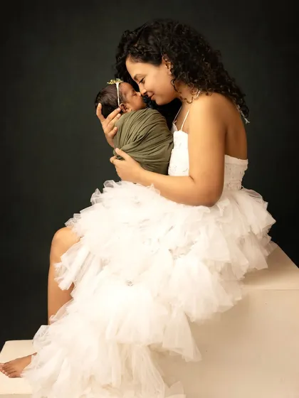 A sweet moment between mother and newborn. She looks down at her sleeping baby with love, highlighting the special bond they share.
